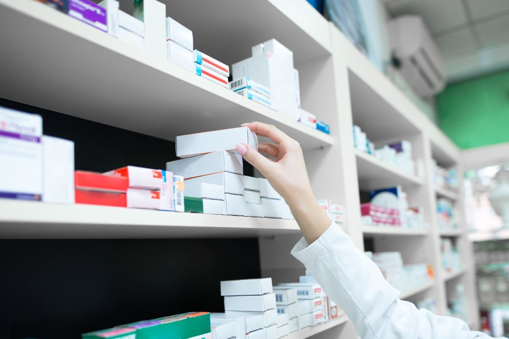 Nahaufnahme: Apothekerhand nimmt Medizinbox aus dem Regal