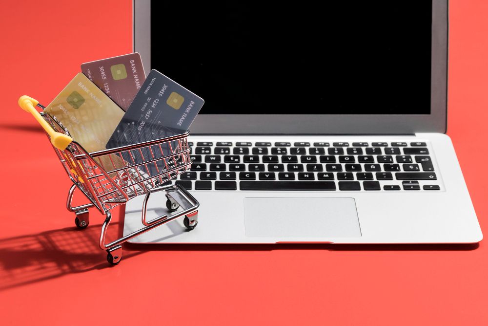 Einkaufswagen mit Kreditkarten vor einem Laptop